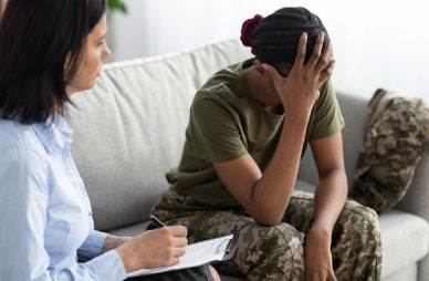 Female psychologist comforting black soldier during therapy session.